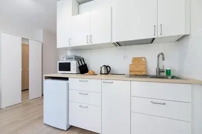 a white kitchen with white cabinets and a microwave at Śródmieście Kątowa Air-conditioned Studio Kraków by Noclegi Renters in Kraków