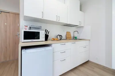 a kitchen with white cabinets and a microwave at Śródmieście Kątowa Air-conditioned Studio Kraków by Noclegi Renters in Kraków