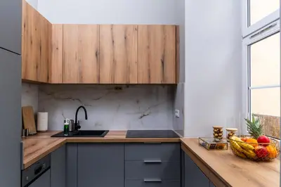 a kitchen with wooden cabinets and a bowl of fruit on a counter at Old Town Luxury Apartment - Rynek Szewska in Kraków