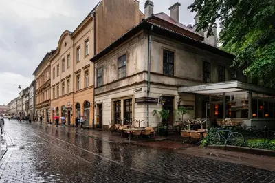 a street with buildings and tables and chairs in the rain at Old Town Luxury Apartment - Rynek Szewska in Kraków
