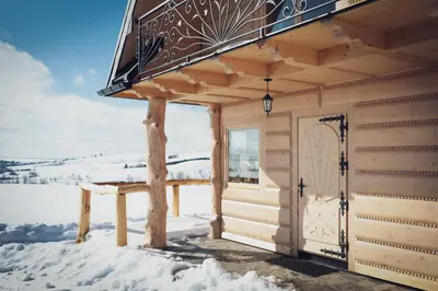 a wooden cabin with a door in the snow at Domek pod lasem in Klikuszowa
