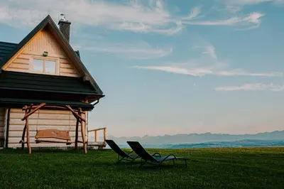 two chairs sitting in the grass next to a house at Domek pod lasem in Klikuszowa