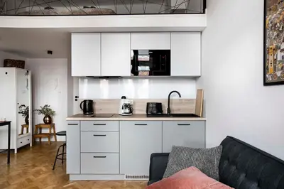 a kitchen with white cabinets and a couch in a living room at Charming Studio with kitchen - Old Town, Main Station in Kraków