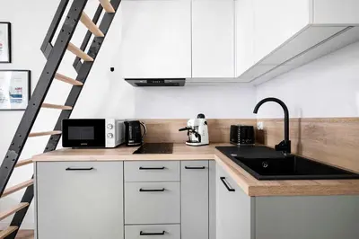 a kitchen with white cabinets and a sink and a ladder at Charming Studio with kitchen - Old Town, Main Station in Kraków