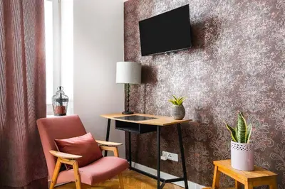 a living room with a chair and a tv on a wall at Charming Studio with kitchen - Old Town, Main Station in Kraków