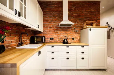 a kitchen with white cabinets and a brick wall at 2-room Apartment with kitchen, heart of Cracow Old Town in Kraków