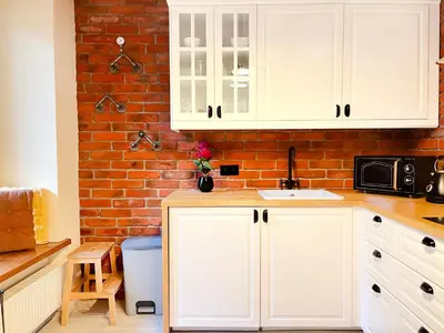 a kitchen with white cabinets and a brick wall at 2-room Apartment with kitchen, heart of Cracow Old Town in Kraków