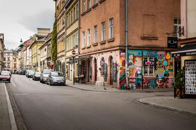 a street with cars parked on the side of a building with graffiti at 2-room Apartment with kitchen, heart of Cracow Old Town in Kraków