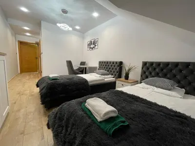 a bedroom with three beds with black blankets and a desk at Mały Książę in Podzamcze