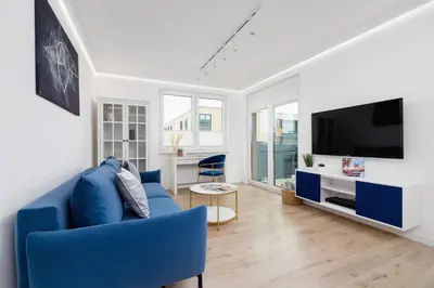 a living room with a blue couch and a tv at Fredry 6 Apartment Premium Łagiewniki by Renters Prestige in Kraków