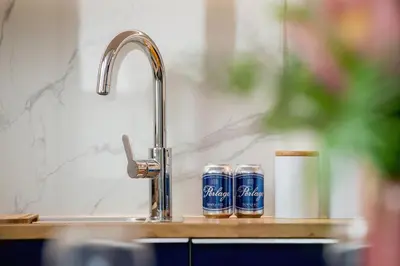 a kitchen sink with two cans of soda at Fredry 6 Apartment Premium Łagiewniki by Renters Prestige in Kraków