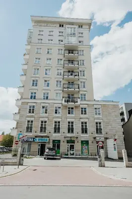 a tall white building with a car parked in front of it at Sky Mountain View Free Parking in Kraków