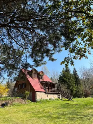 an old house with a red roof on a field at Izdebka na Podchybiu in Izdebnik