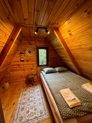a bedroom with a bed in a wooden cabin at Izdebka na Podchybiu in Izdebnik