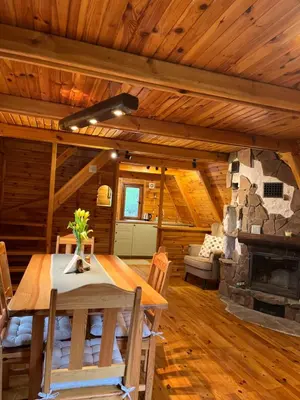 a dining room with a table and a stone fireplace at Izdebka na Podchybiu in Izdebnik