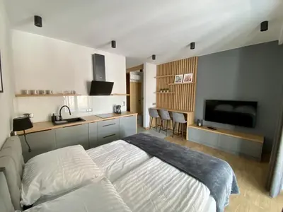 a bedroom with a white bed and a kitchen at Apartamenty WIERCHY in Klikuszowa