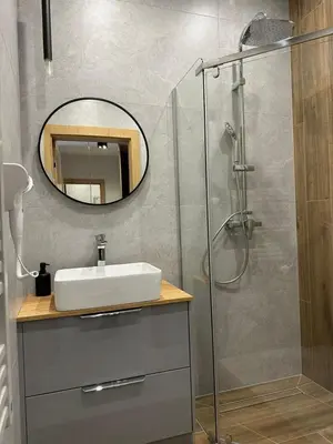a bathroom with a sink and a shower with a mirror at Apartamenty WIERCHY in Klikuszowa