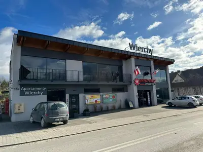 a building with a car parked in front of it at Apartamenty WIERCHY in Klikuszowa