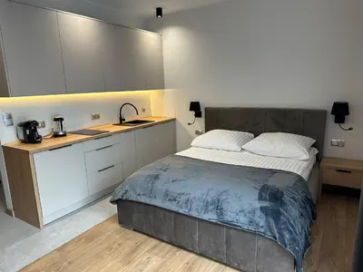 a bedroom with a bed and a kitchen with white cabinets at Apartamenty WIERCHY in Klikuszowa