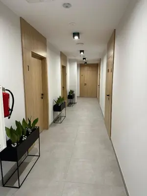 an empty hallway with wooden doors and potted plants at Apartamenty WIERCHY in Klikuszowa