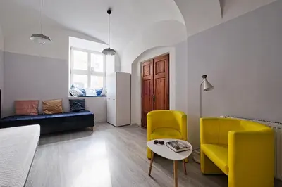 a living room with yellow chairs and a table at Urban Nest Apartments Party Szewska21 in Kraków