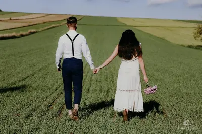 a man and woman walking through a field holding hands at Zaczarowana Furmanka in Antolka