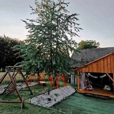 a tree and a house with a swing at Zaczarowana Furmanka in Antolka