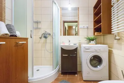 a bathroom with a washing machine and a sink at Przytulny apartament z parkingiem blisko Tauron Areny in Kraków