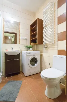 a bathroom with a washing machine and a toilet at Przytulny apartament z parkingiem blisko Tauron Areny in Kraków