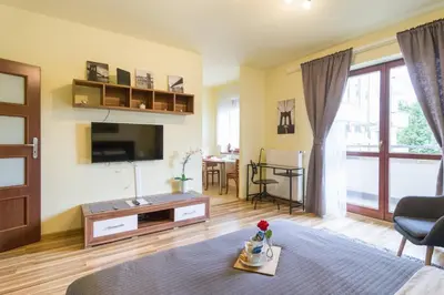 a living room with a bed and a tv at Przytulny apartament z parkingiem blisko Tauron Areny in Kraków
