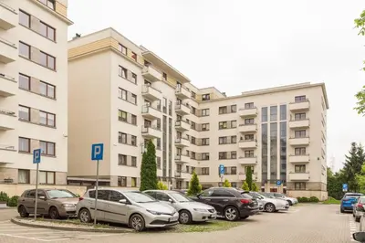 a row of cars parked in a parking lot in front of a building at Przytulny apartament z parkingiem blisko Tauron Areny in Kraków