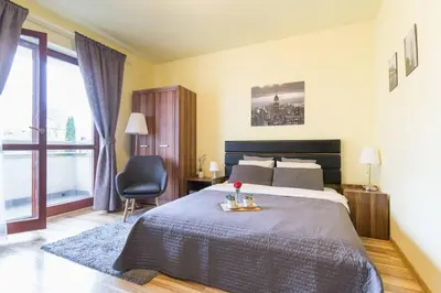 a bedroom with a bed and a chair and a window at Przytulny apartament z parkingiem blisko Tauron Areny in Kraków