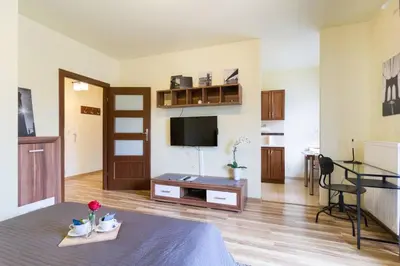 a living room with a bed and a flat screen tv at Przytulny apartament z parkingiem blisko Tauron Areny in Kraków
