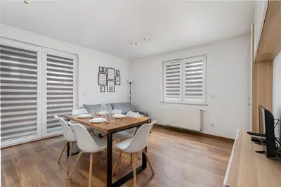 a dining room with a wooden table and white chairs at Zabłocie Apartment Best Location to Explore Krakow in Kraków