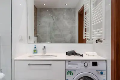 a bathroom with a sink and a washing machine at Zabłocie Apartment Best Location to Explore Krakow in Kraków