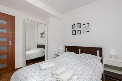 a white bedroom with a bed and a mirror at Zabłocie Apartment Best Location to Explore Krakow in Kraków