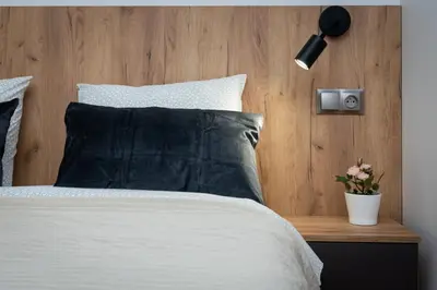 a bed with a black pillow and a wooden headboard at Romanowicza Prestige Place in Kraków