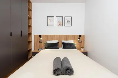 a bedroom with a bed with two pairs of slippers at Romanowicza Prestige Place in Kraków