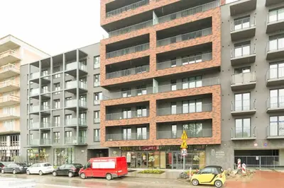a tall building with cars parked in front of it at Zabłocie Cozy Escape in Kraków