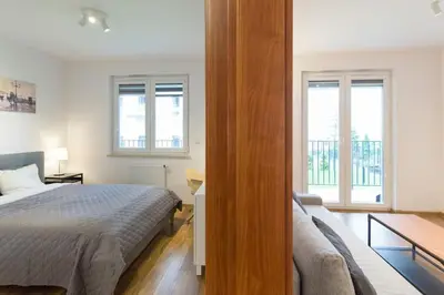 a bedroom with a bed and a couch and windows at Zabłocie Cozy Escape in Kraków