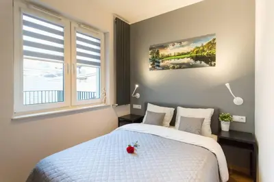 a bedroom with a white bed and two windows at Cozy apartment with garden prestigious location in Kraków