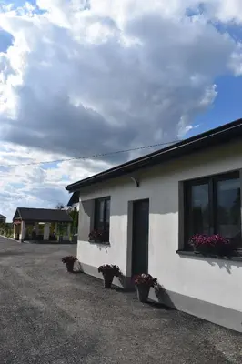 a white building with potted plants on the side of it at Domki - Apartamenty Complex in Zator