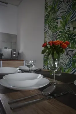 a table with a white plate and a vase of flowers at Domki - Apartamenty Complex in Zator