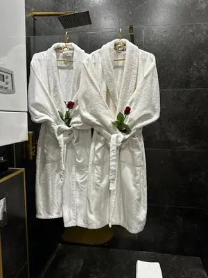 two white robes hanging on a wall in a bathroom at Apartament z Jacuzzi Kraków SHINE Starowiślna in Kraków