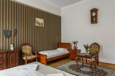 a bedroom with two beds and a table and chairs at The Spiski Palace Apartments in Kraków