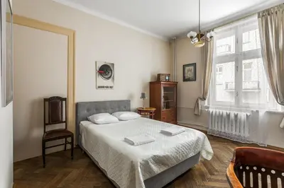 a bedroom with a bed and a chair and a window at The Spiski Palace Apartments in Kraków