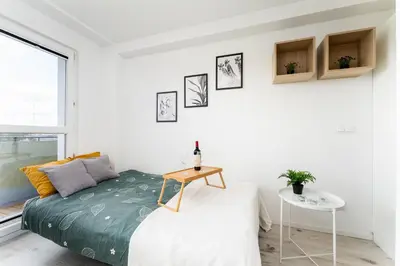 a white bedroom with a bed and a table at Czarnowiejska Mini Studio with loggia in Kraków