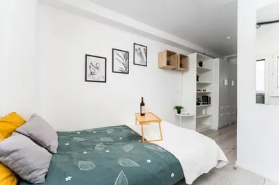 a bedroom with a bed with a green blanket at Czarnowiejska Mini Studio with loggia in Kraków