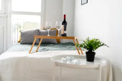 a table with two glasses and a bottle of wine on a bed at Czarnowiejska Mini Studio with loggia in Kraków
