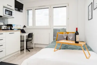 a white kitchen with a table with wine glasses on a bed at Czarnowiejska Mini Studio with loggia in Kraków